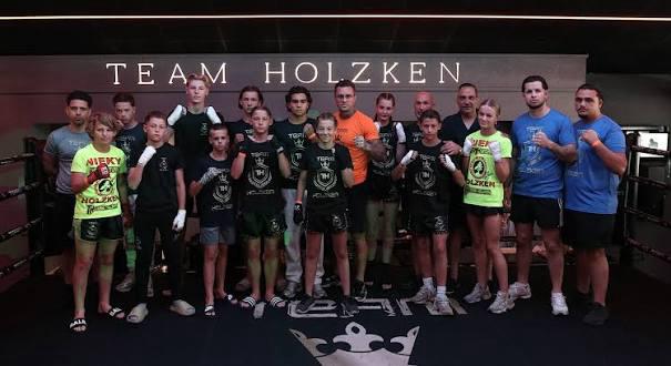 Jeugdleden en trainers van Team Holzken samen in de nieuwe gym